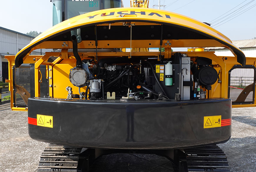 Yuchai Americas excavator engine compartment open, revealing complex machinery, hydraulics, and cooling systems beneath yellow hood with Yuchai branding