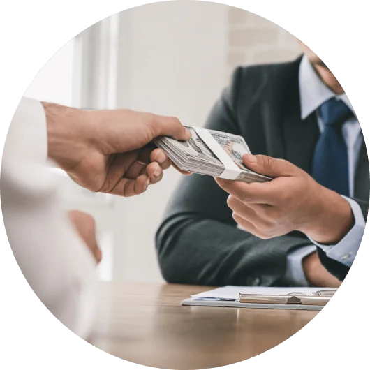 Close-up of hands exchanging money, with one person in a business suit receiving cash from another person