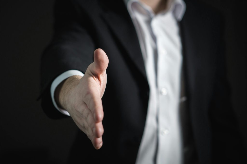 Businessman in a suit extending hand for a handshake, representing Yuchai Americas' professional approach to customer relations